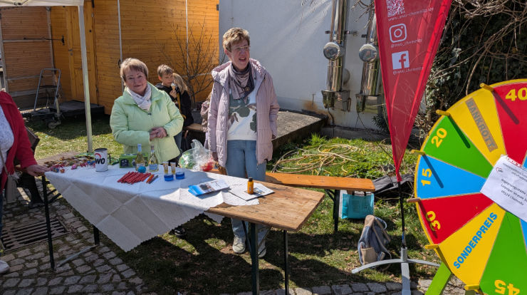 zwei Frauen stehen an einem Tisch, auf dem Werbematerialien liegen