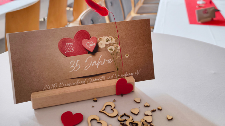Eine Karte mit der Aufschrift 35 Jahre steht auf einem Tisch. Davor liegen Herzen als Streudeko.